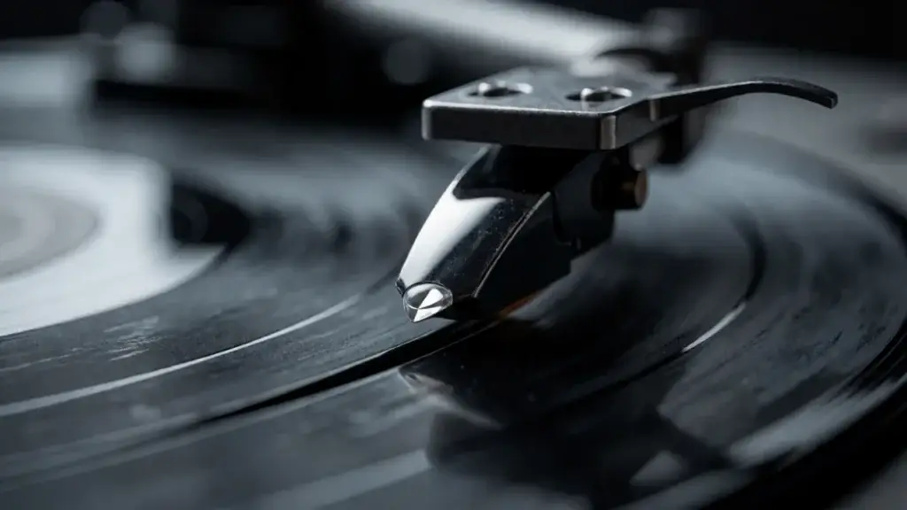 Belt-drive beginner turntable with dust cover open on an oak sideboard beside bookshelf speakers &ndash; detail view